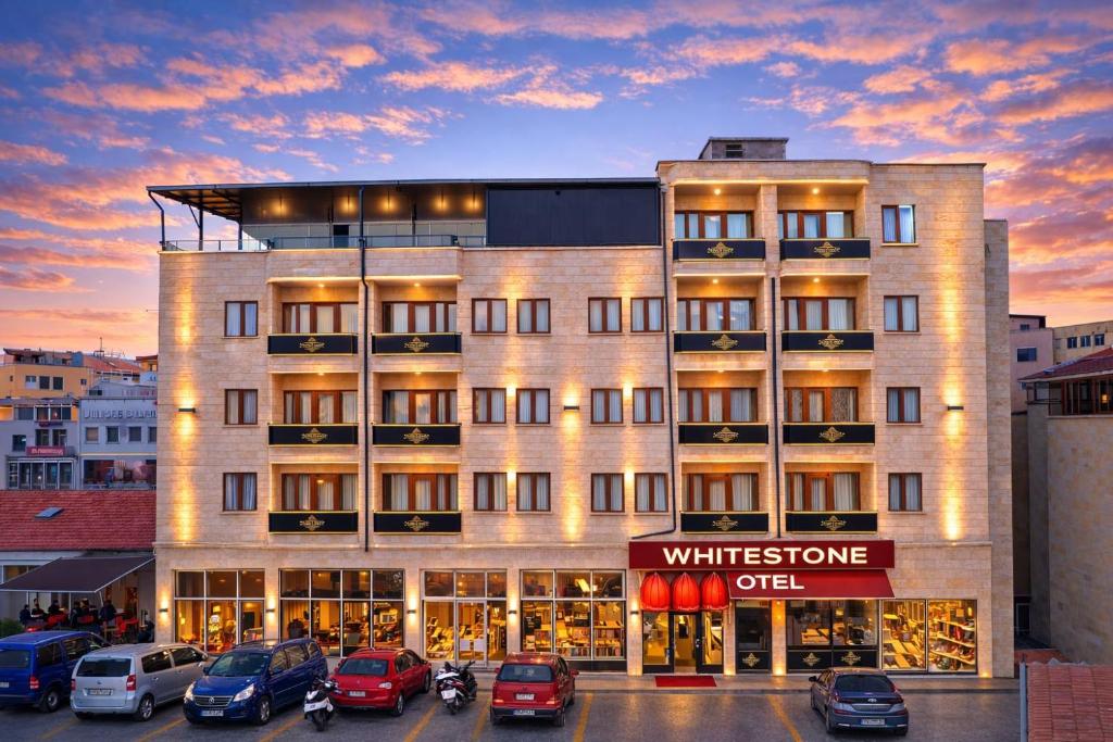 a building with cars parked in a parking lot at Whitestone Hotel in Nevşehir