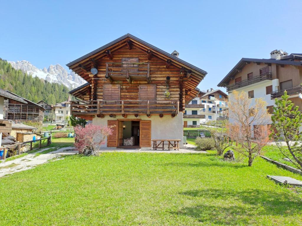 a log house with a green lawn in front of it at Tabia Maredane in Falcade