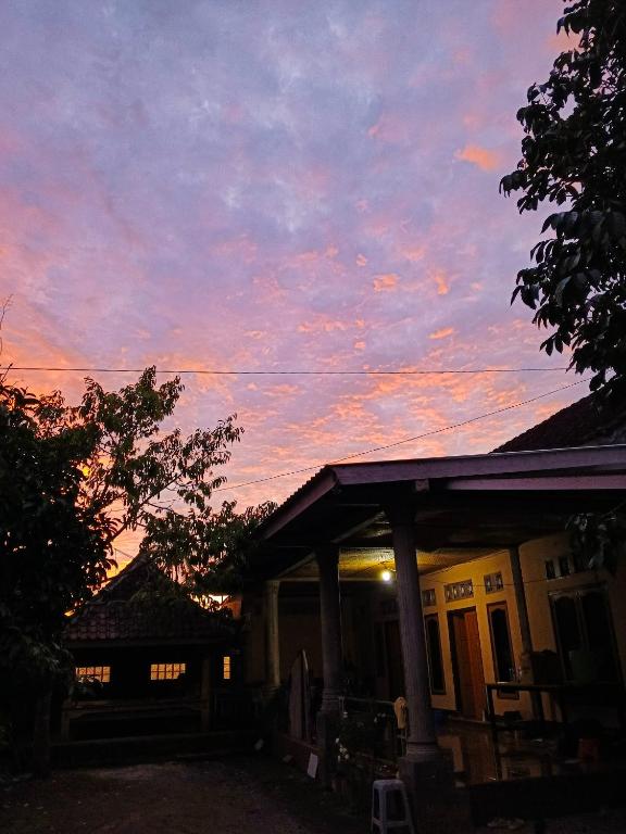 a house with a sunset in the sky at Keluncing Field Homestay in Tetebatu
