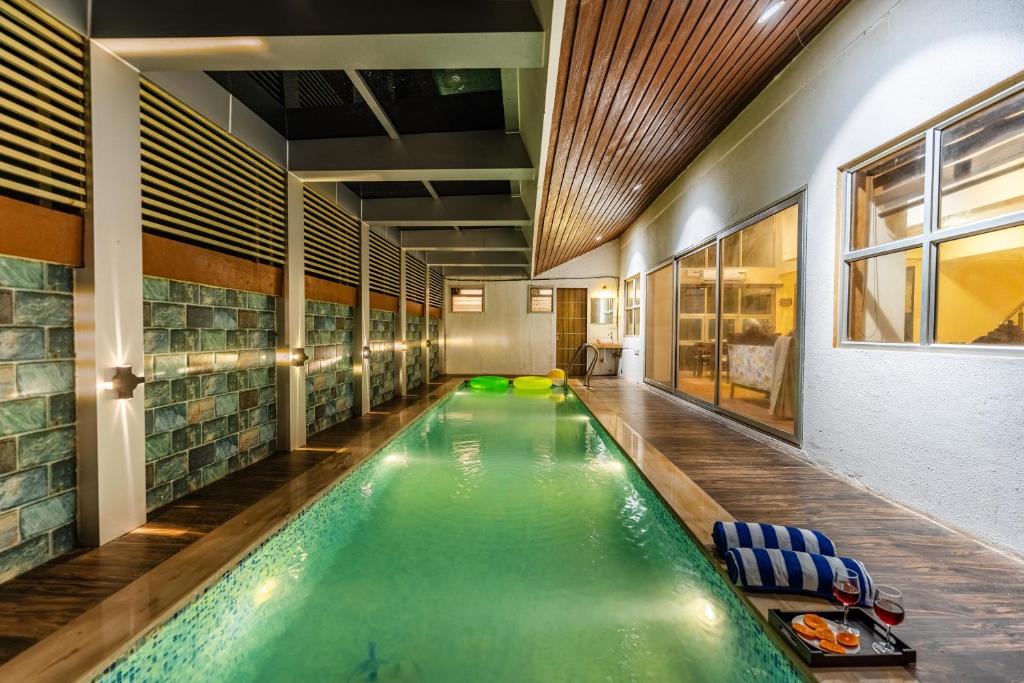 an indoor pool in a building with chairs and a swimming pool at Gauri Villa by ELIVAAS With Pool, Lounge, Garden & Bathtub With 360 Panoramic Hill Views Near Waterfalls in Kasāra
