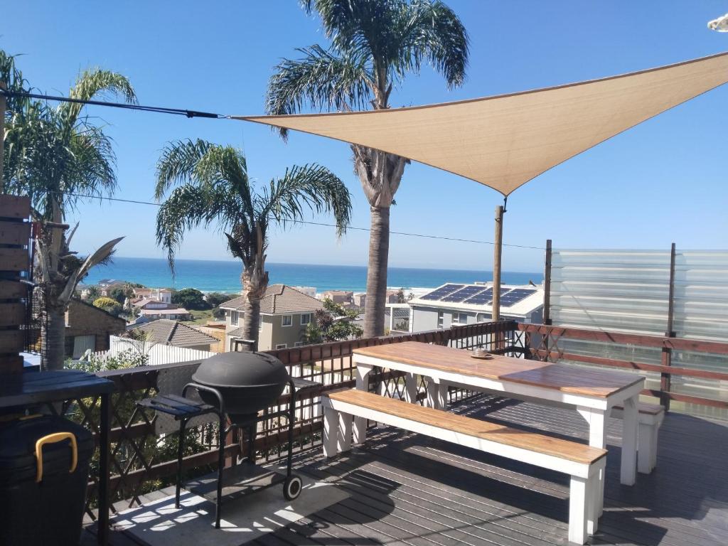 a grill and picnic table on a deck with the beach at The Deck in Jeffreys Bay