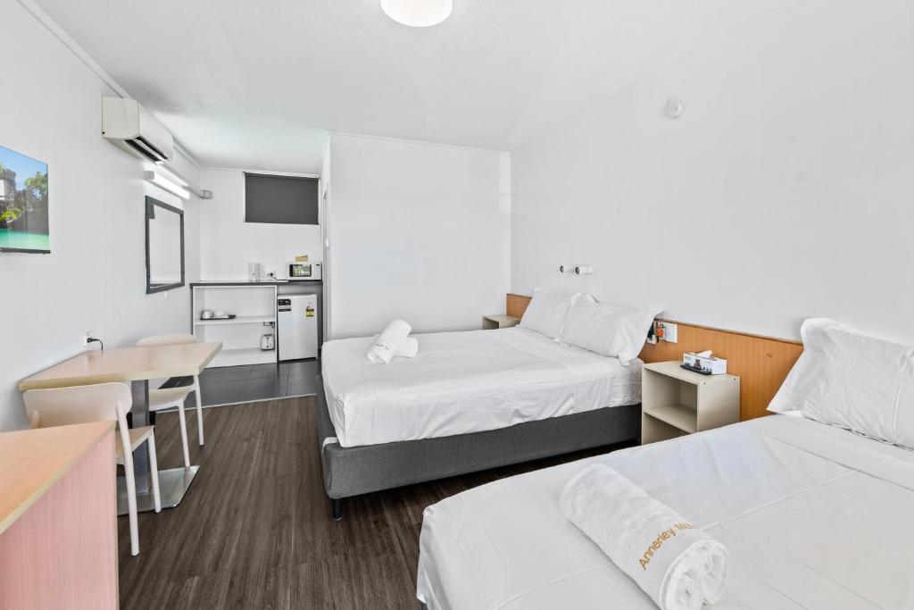 a room with two beds and a table and a kitchen at Annerley Motor Inn in Brisbane
