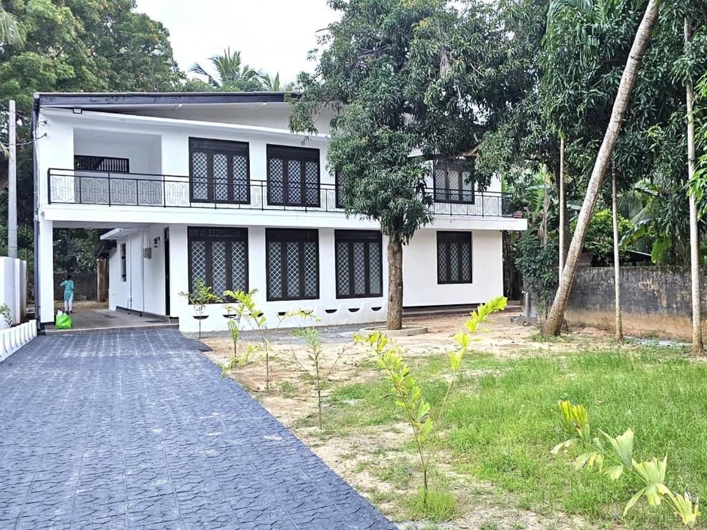 a white house with a walkway in front of it at Royal Star Guest House in Jaffna