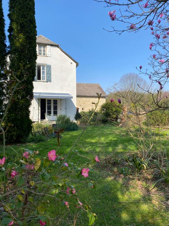 a white house with pink flowers in the yard at Gîte Asaliah in Sainte-Colome