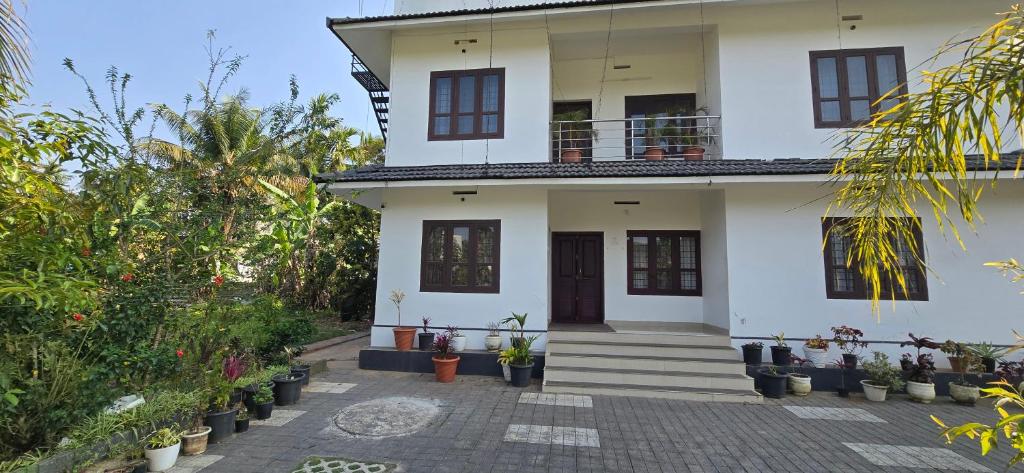 a white house with plants in front of it at Brighton Hostel Stays in Sultan Bathery