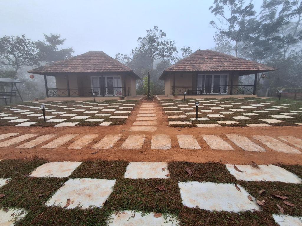 a house with a checkered floor and two buildings at Vidman Homey Huts in Tindummal
