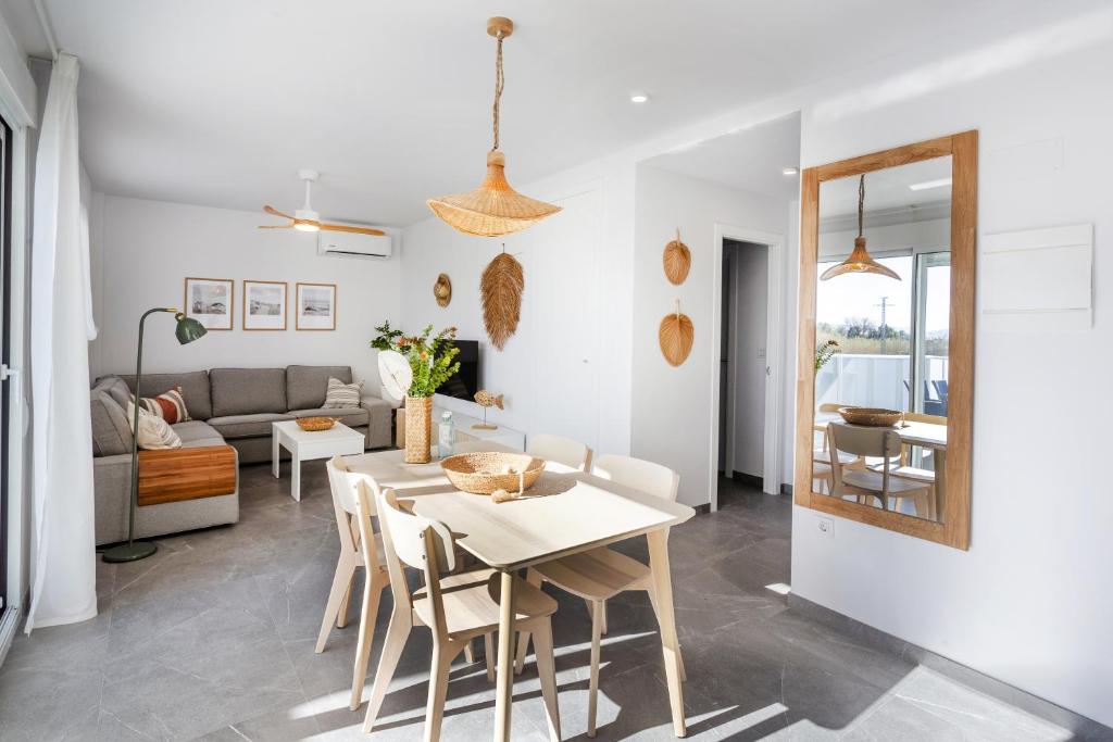 a dining room and living room with a table and chairs at AT Ponent I B3 in La Playa de la Torre de Piles