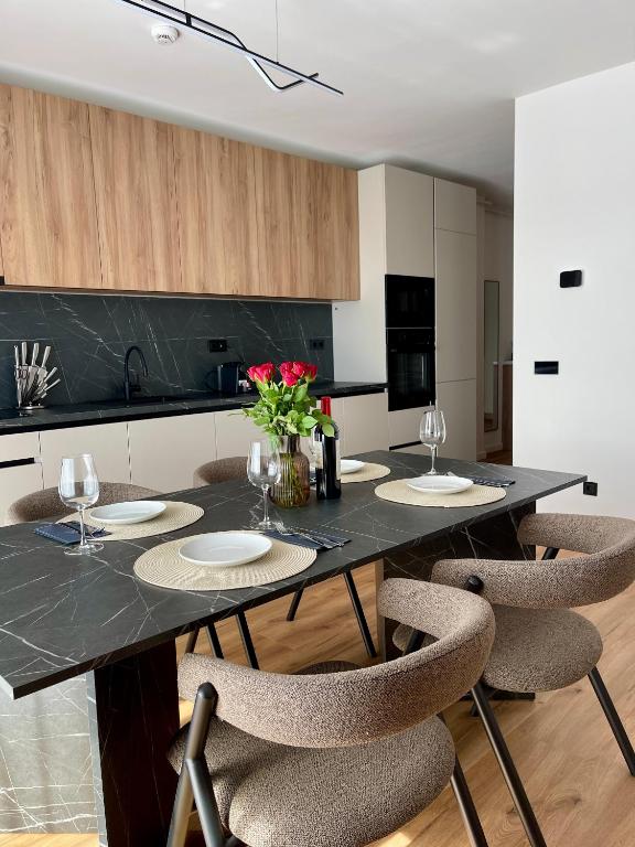 a kitchen with a black table with chairs and flowers at Cashmere Apartment in Cluj-Napoca
