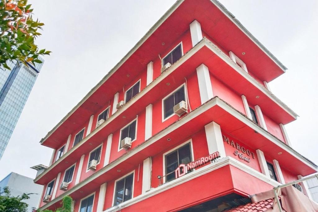 a red and white building with birds on the balcony at NamRoom at Margot Jaksa in Jakarta