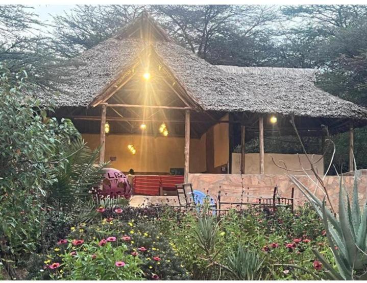 a house with a thatched roof and chairs in a garden at Empiris homestay in Sekenani