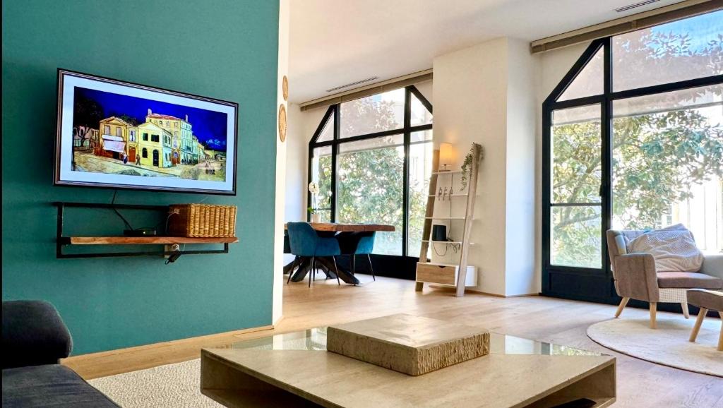 a living room with a couch and a tv on a wall at - Magnifique appartement climatisé 92m2, spacieux et cosy, au cœur de Vichy in Vichy