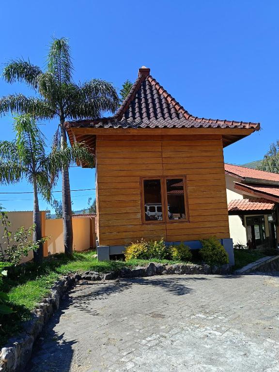 a house with a palm tree in front of it at Uciek Tengger Hotel Bromo in Ngadisari