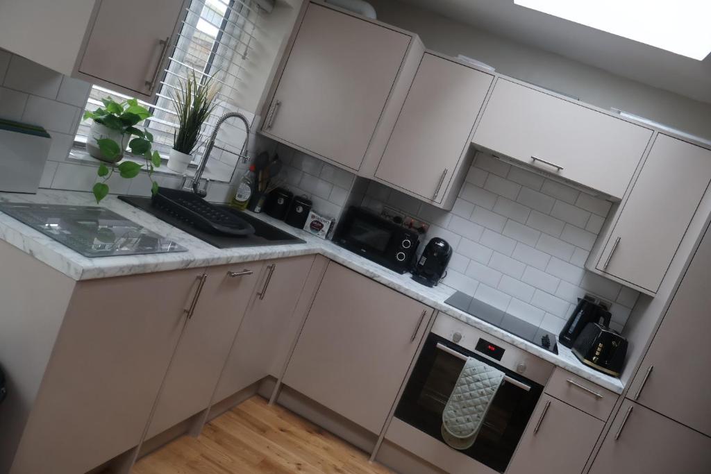 a white kitchen with white cabinets and a sink at Airy 3 bedroom House in Norwood