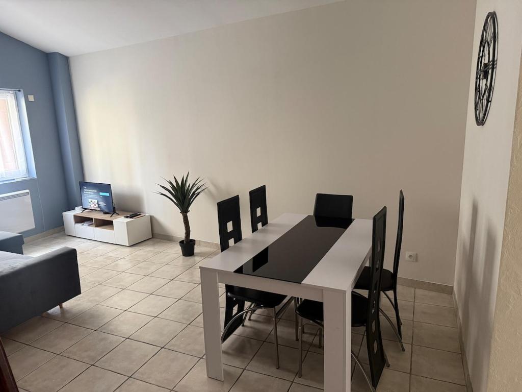 a dining room with a white table and black chairs at Studio Cardinal in Renage