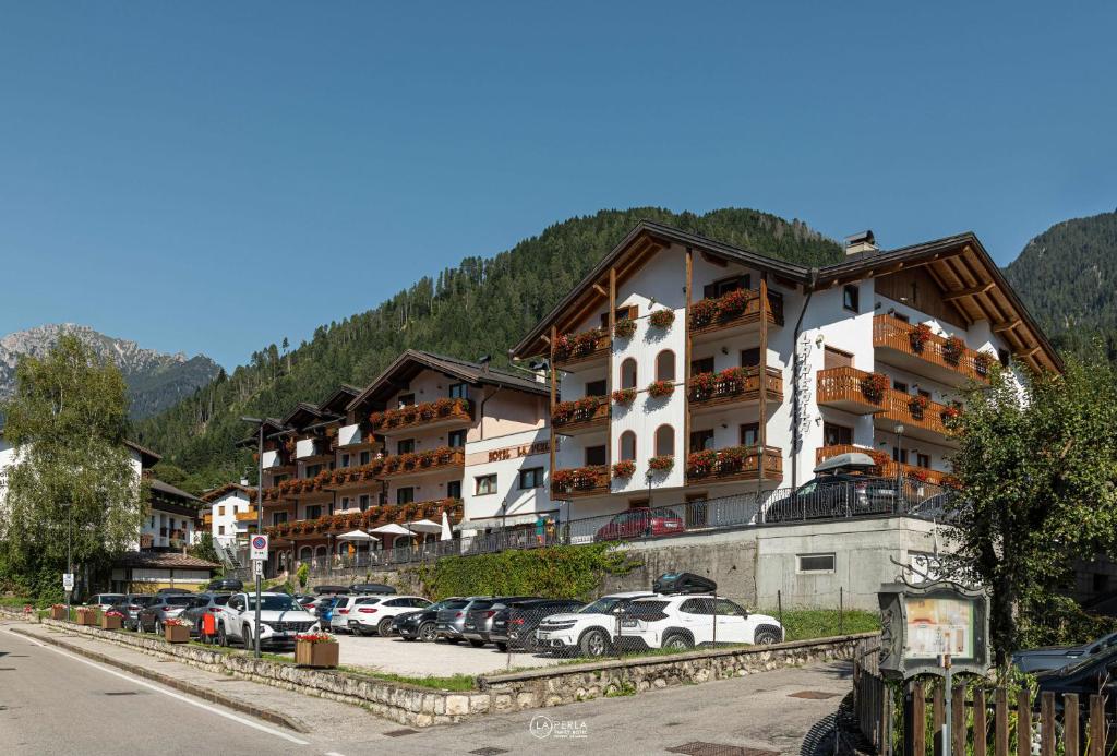 a large building with cars parked in a parking lot at Family Hotel La Perla in Fiera di Primiero