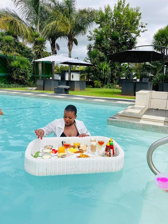 a man in a pool with a tray of food at Africa Prestige Boutique Hotel in Benoni