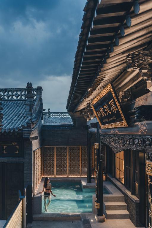 a woman standing in a pool in front of a building at PingYao Chengfu Jinyuan Hotel in Pingyao