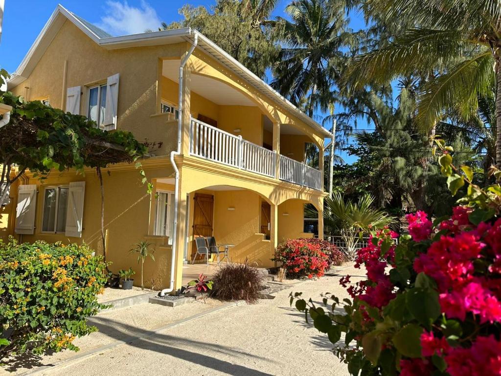 a yellow house with flowers in front of it at Korail Bleu in Rodrigues Island