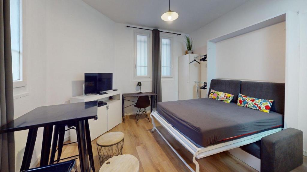 a small bedroom with a bed and a desk at chaleureux studio Maillart centre ville in Le Havre