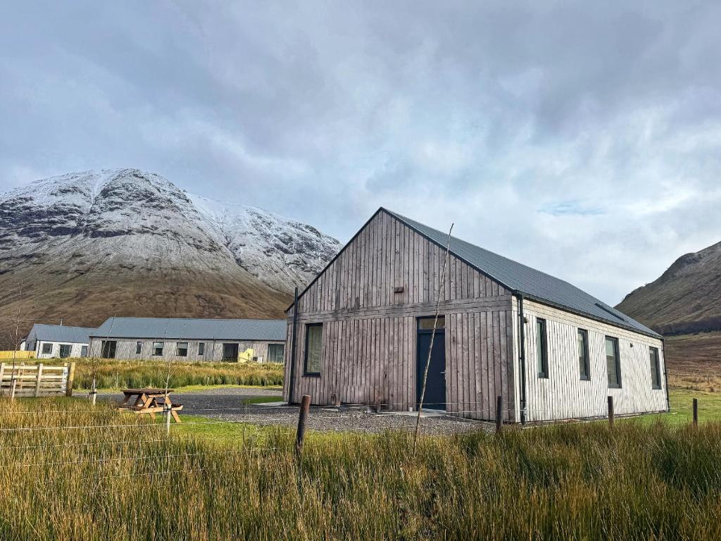 a barn in a field with mountains in the background at Auch - Trail Cabins in Bridge of Orchy