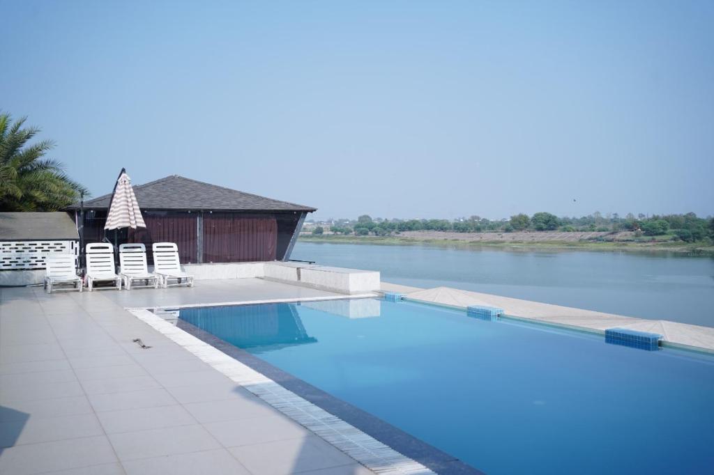 a swimming pool next to a body of water at Riviera Resort and Hotel in Durg