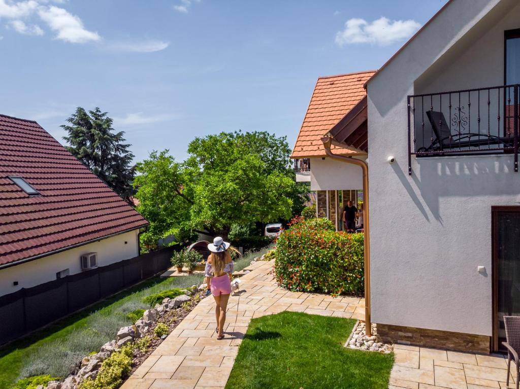 a woman with an umbrella standing in the yard of a house at Pilger Apartments in Tihany