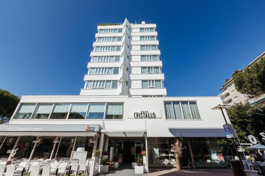 a tall white building with white chairs in front of it at Hotel Cristallo in Riccione