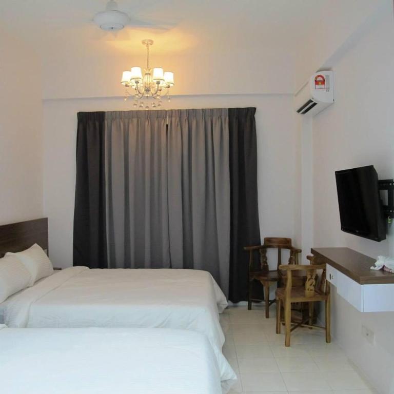 a bedroom with two beds and a window with a television at Pangkor Lot 10 Moonlight in Kampong Sungai Udang