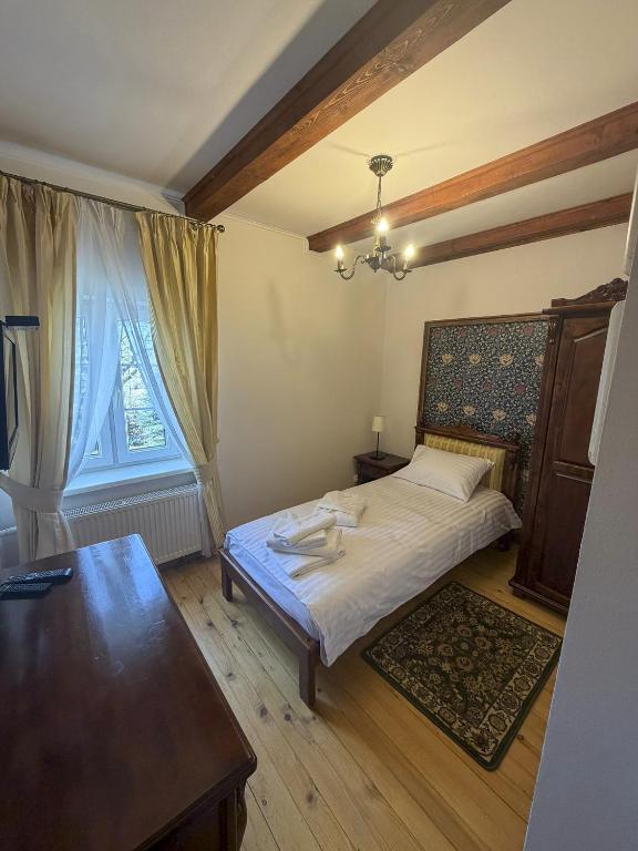 Single bedroom with wooden beams, bedside table, wardrobe, desk, and neatly made bed.
