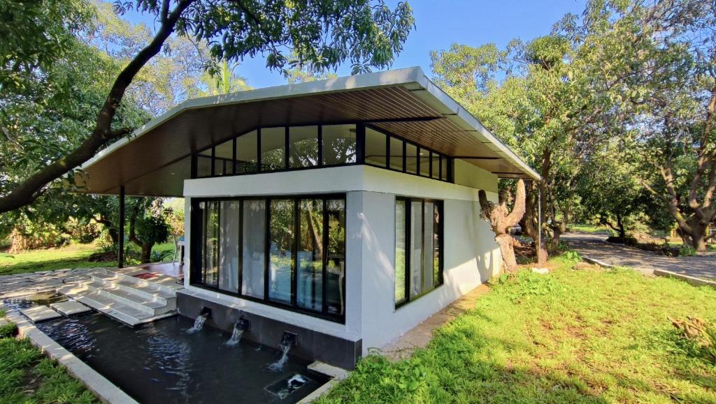 a house with a pond in front of it at The Rising Sun Farm Karjat - Luxury Stays - Couple Friendly in Karjat