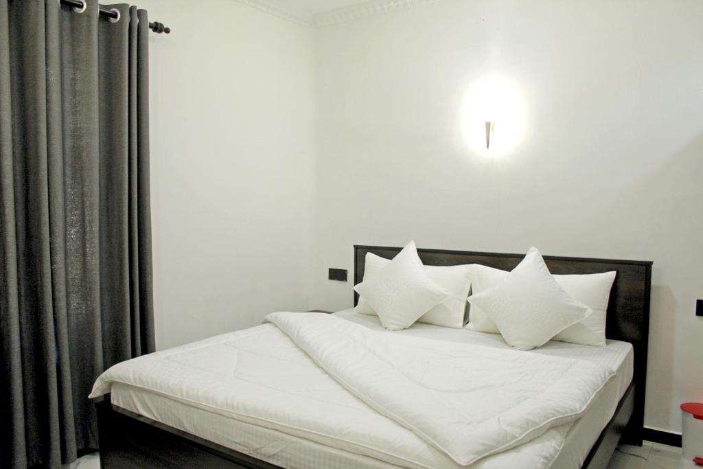 a bedroom with a white bed with white sheets and pillows at R&B Guest House in Jaffna