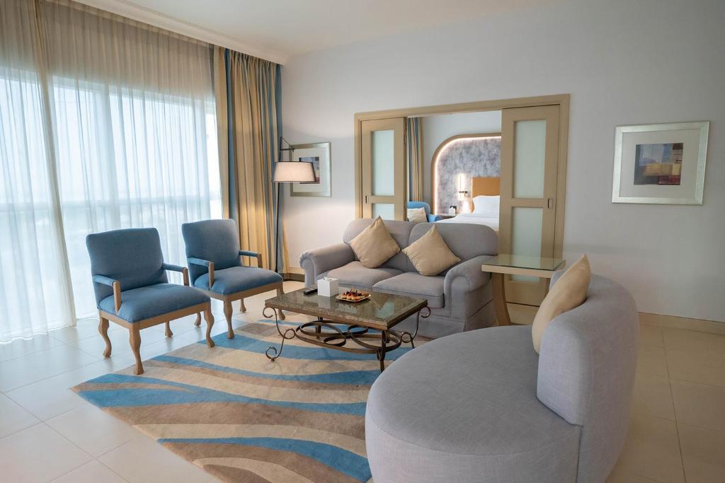 a living room with a couch and chairs in a hotel room at Sheraton Khalidiya Hotel in Abu Dhabi