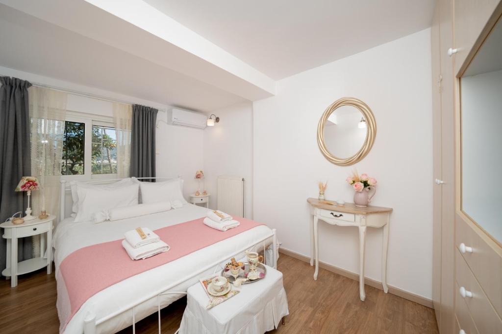 a white bedroom with a large bed and a mirror at Livingstone House in Porto Rafti