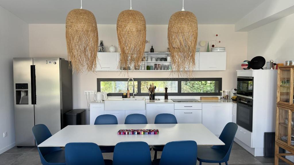 a kitchen with a white table and blue chairs at Villa Koad - piscine privee in Trébeurden