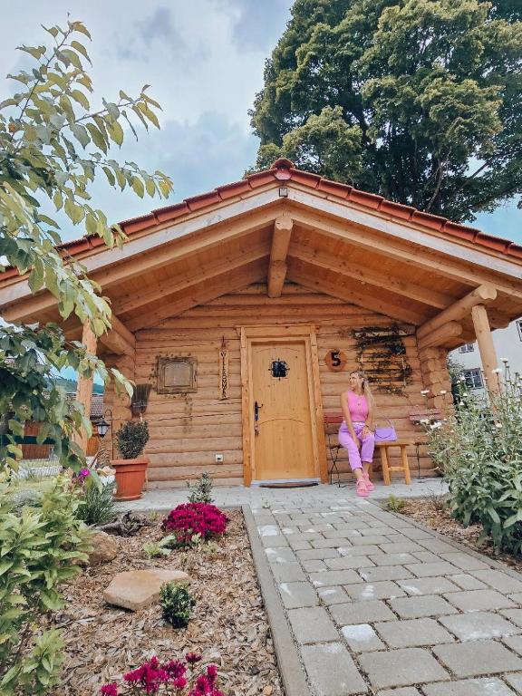 a woman sitting on a bench in front of a cabin at Chalet Hüttendorf 49 gradnord in Bayerisch Eisenstein
