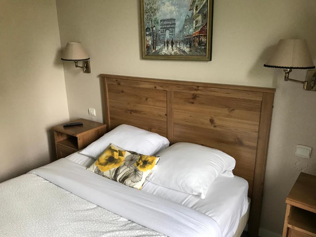 a bed with two pillows on it in a bedroom at LOGIS Hôtel & Restaurant - Au Bord du Lac in Saint-Rémy-lès-Chevreuse
