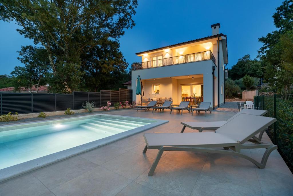a backyard with a swimming pool and a house at Villa Hidden with heated pool in Dobrinj