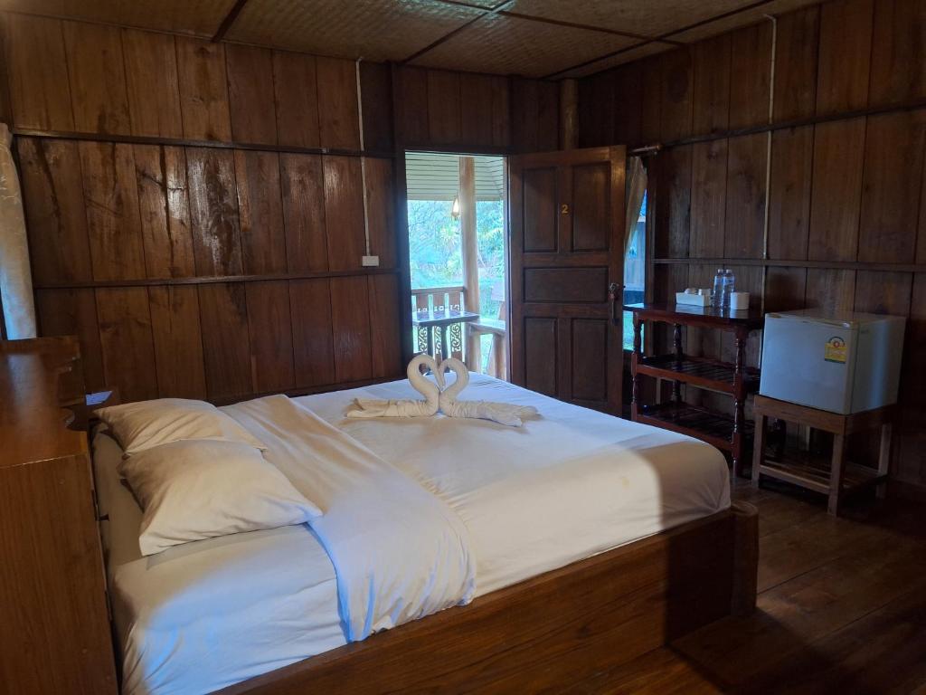 a large bed in a room with wooden walls at Tribal Pai in Pai