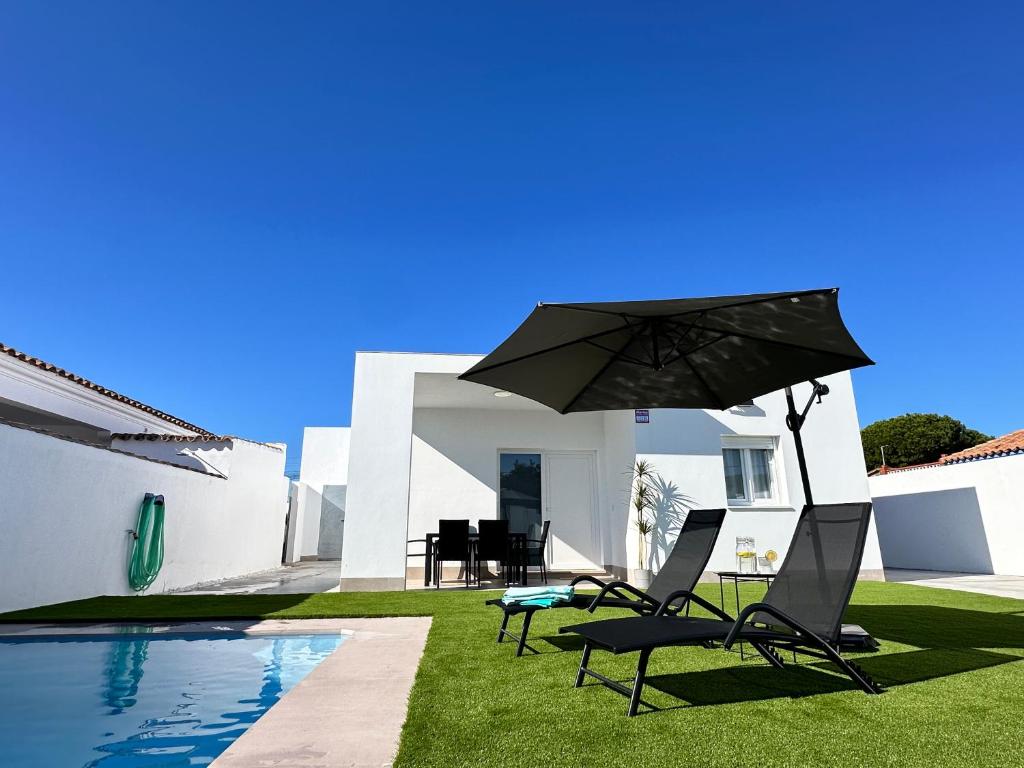 two chairs and an umbrella next to a pool at Chalet Chiclana in Chiclana de la Frontera