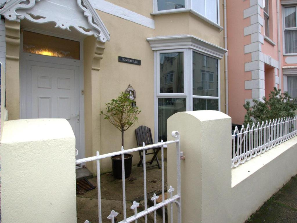 a white fence in front of a house with a door at 6 Bed in Tenby oc-fb220 in Tenby