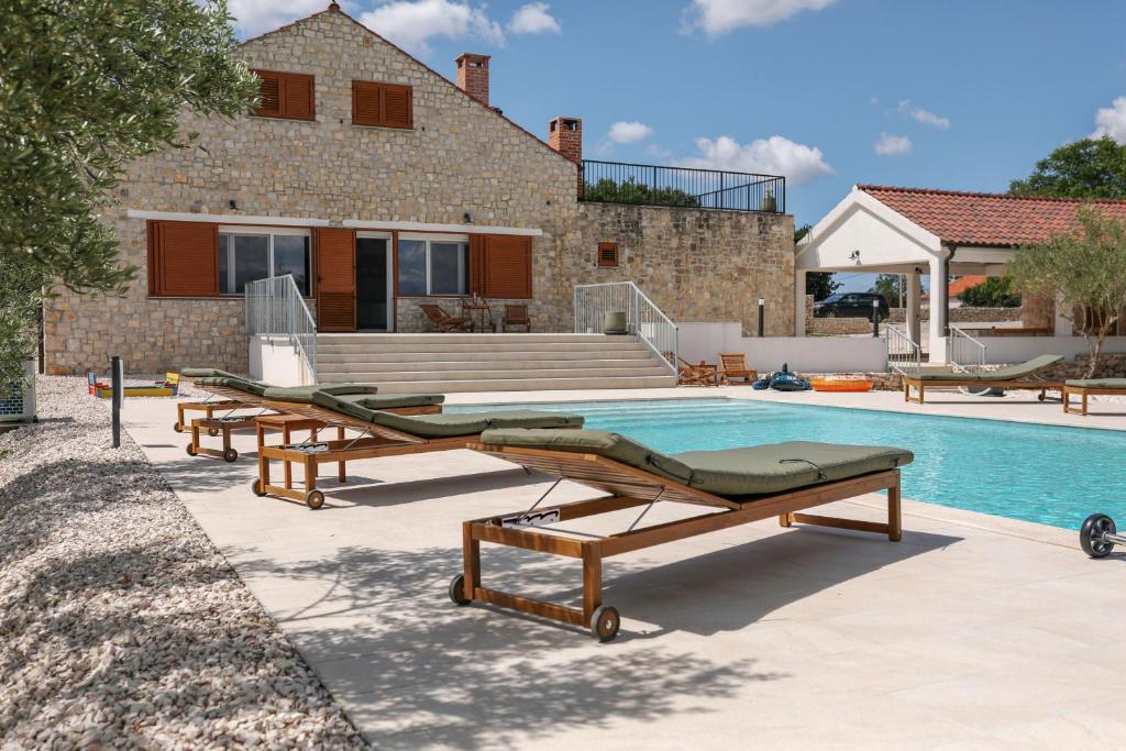a swimming pool with two lounge chairs next to a house at Demare in Gospić