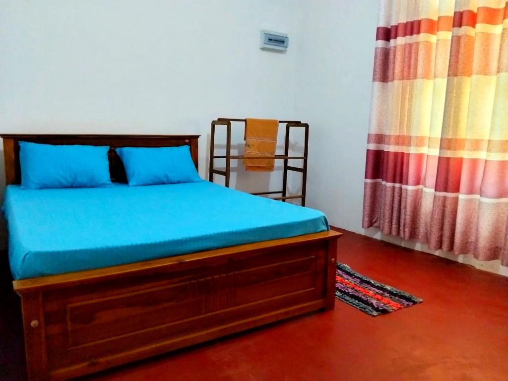 a bedroom with a bed with blue sheets and a window at Ramanayaka Serenity Villa in Bandarawela