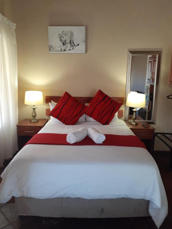 a bedroom with a large white bed with red pillows at Noma-Nini Lodge in White River