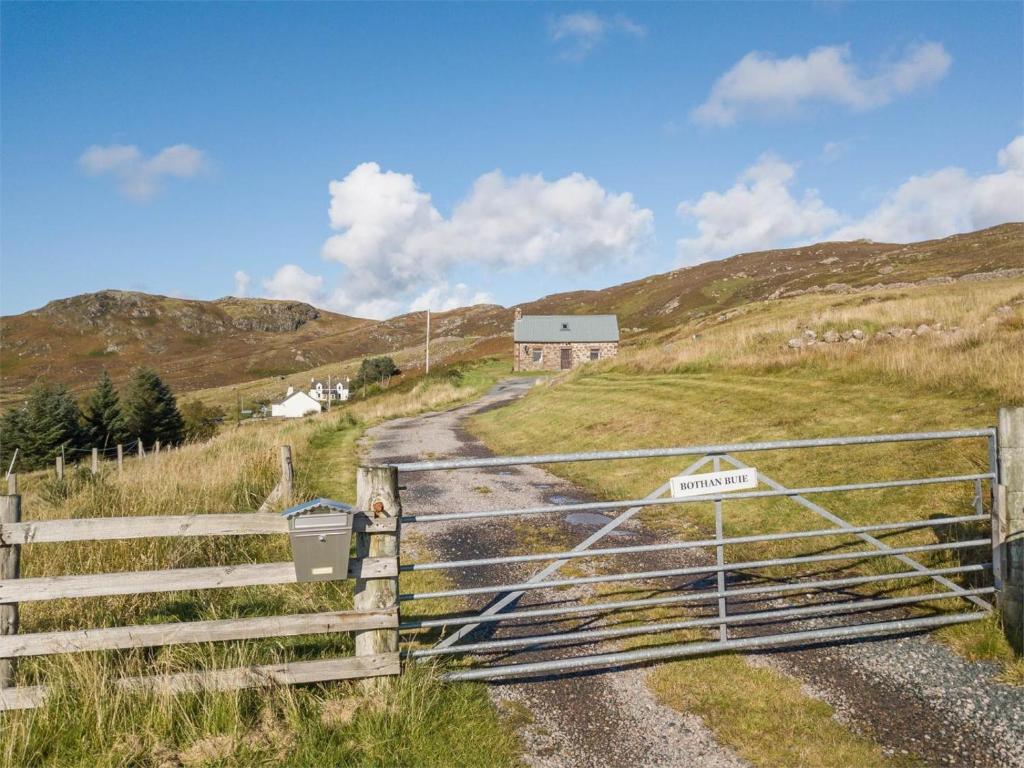 a gate on a hill with a house in the background at 1 Bed in Gairloch oc-ca044 in Gairloch
