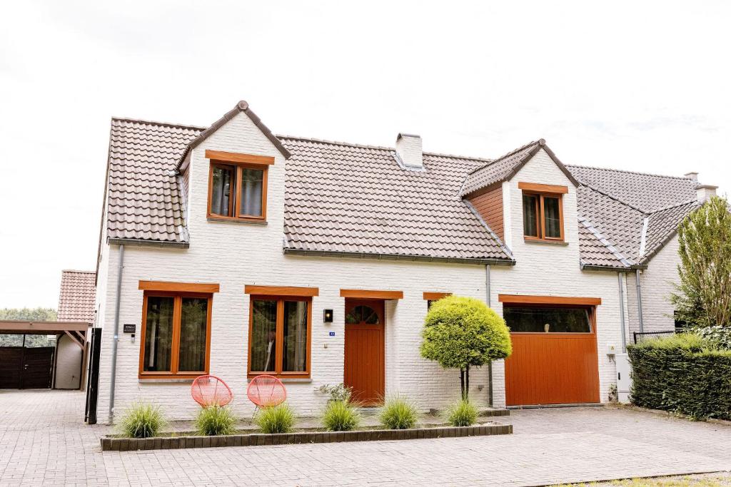 a white house with an orange garage at Le Louis Vakantiehuis in Lanaken