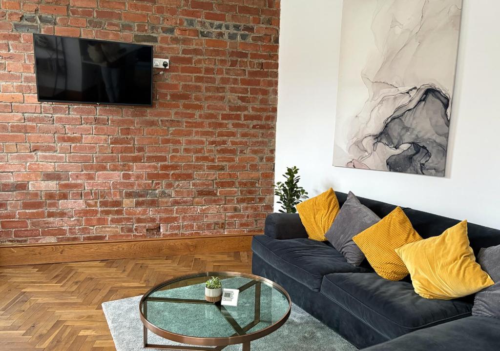 a living room with a black couch and a brick wall at Stylish 1-Bedroom Apartment in Chapel Allerton with Free Parking in Moortown