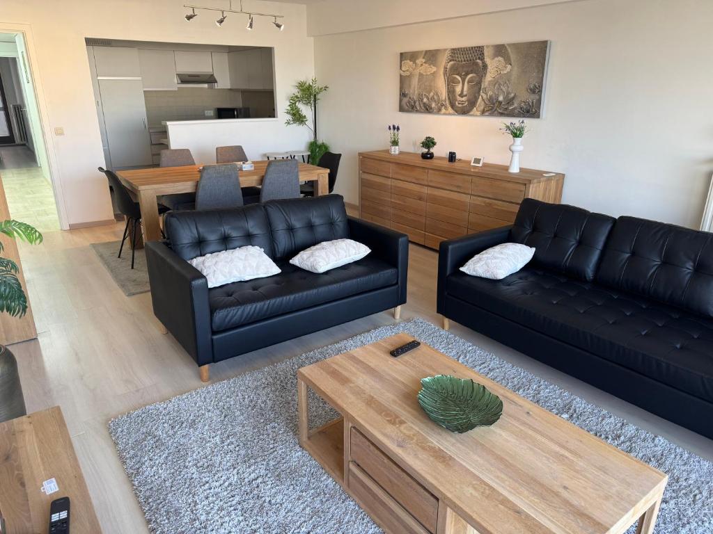 a living room with two black couches and a table at Casa Ghentele in Blankenberge