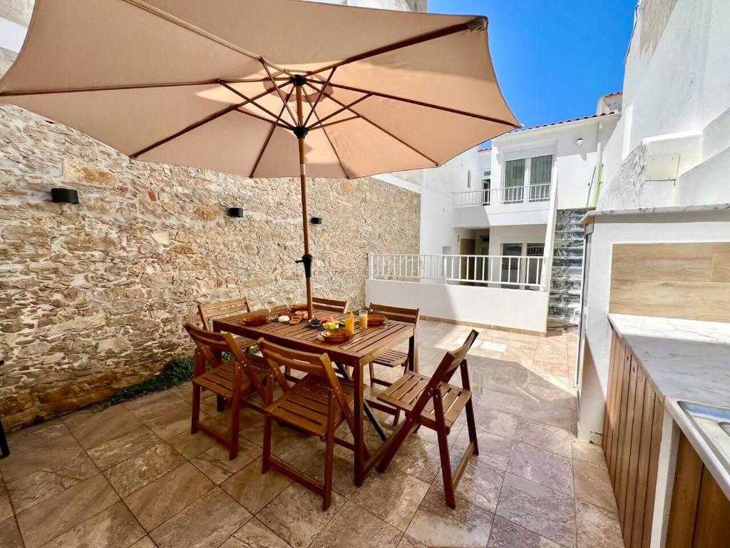 a table and chairs with an umbrella on a patio at Cor de Mar • Pátio • 2 Quartos • Centro Histórico in Peniche