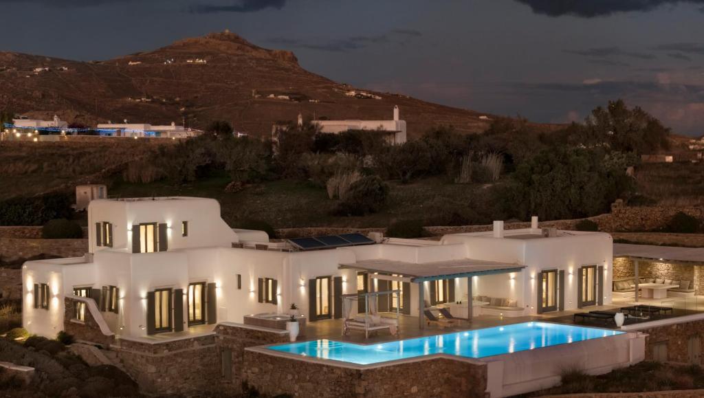a large white house with a swimming pool at night at Margi Villas in Mikonos
