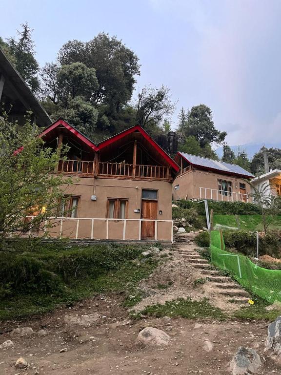a house on a hill next to a dirt road at Private Mudhouse Duplex Cottage by Kahani in Jibhi